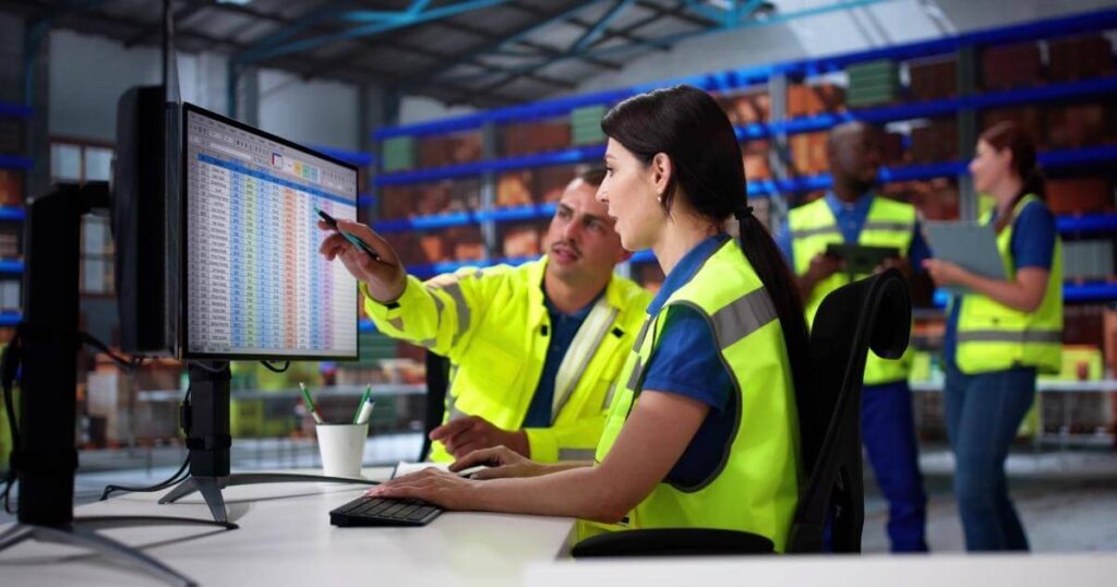 warehouse manager and worker looking at numbers on computer