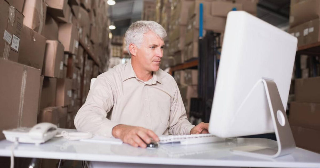 warehouse manager looking at labor market conditions on monitor