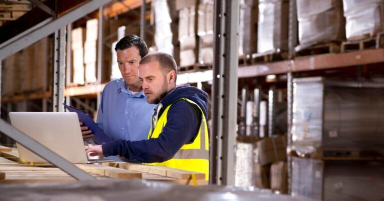 warehouse worker and supervisor looking at laptop