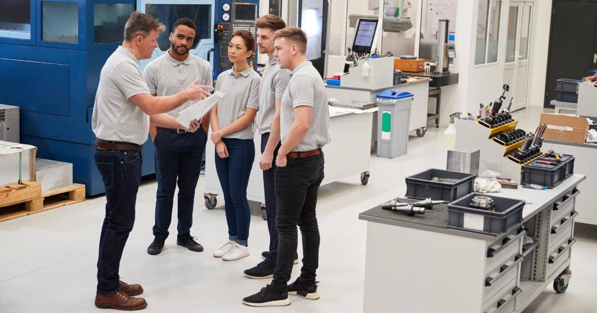mix of part time and full time workers on production floor talking to manager