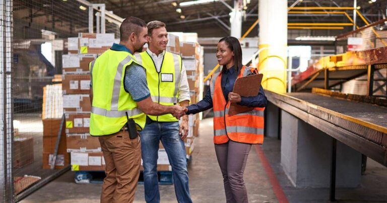 manufacturing workers smiling and shaking hands on first day